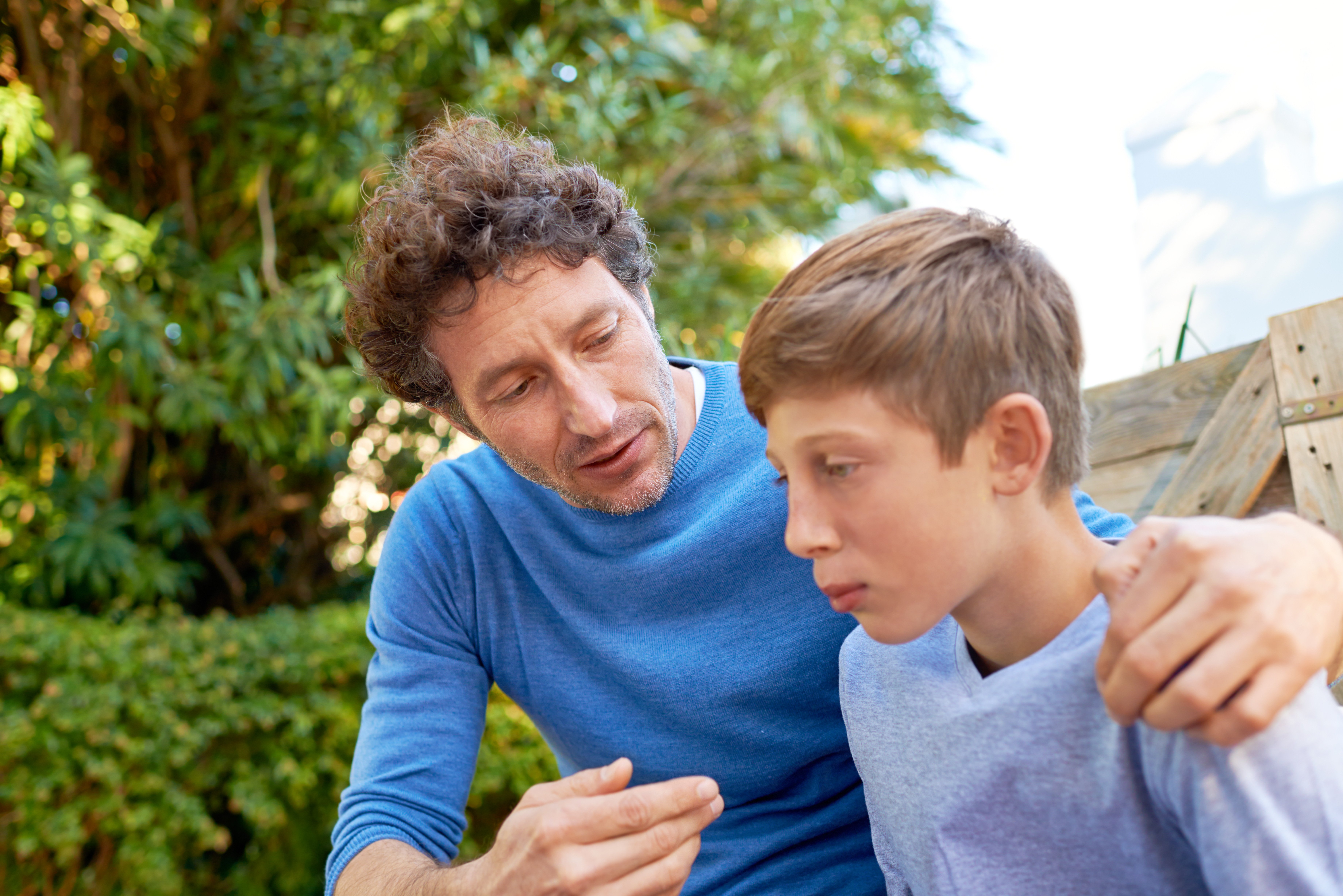 Student and father having a tough conversation outdoors.